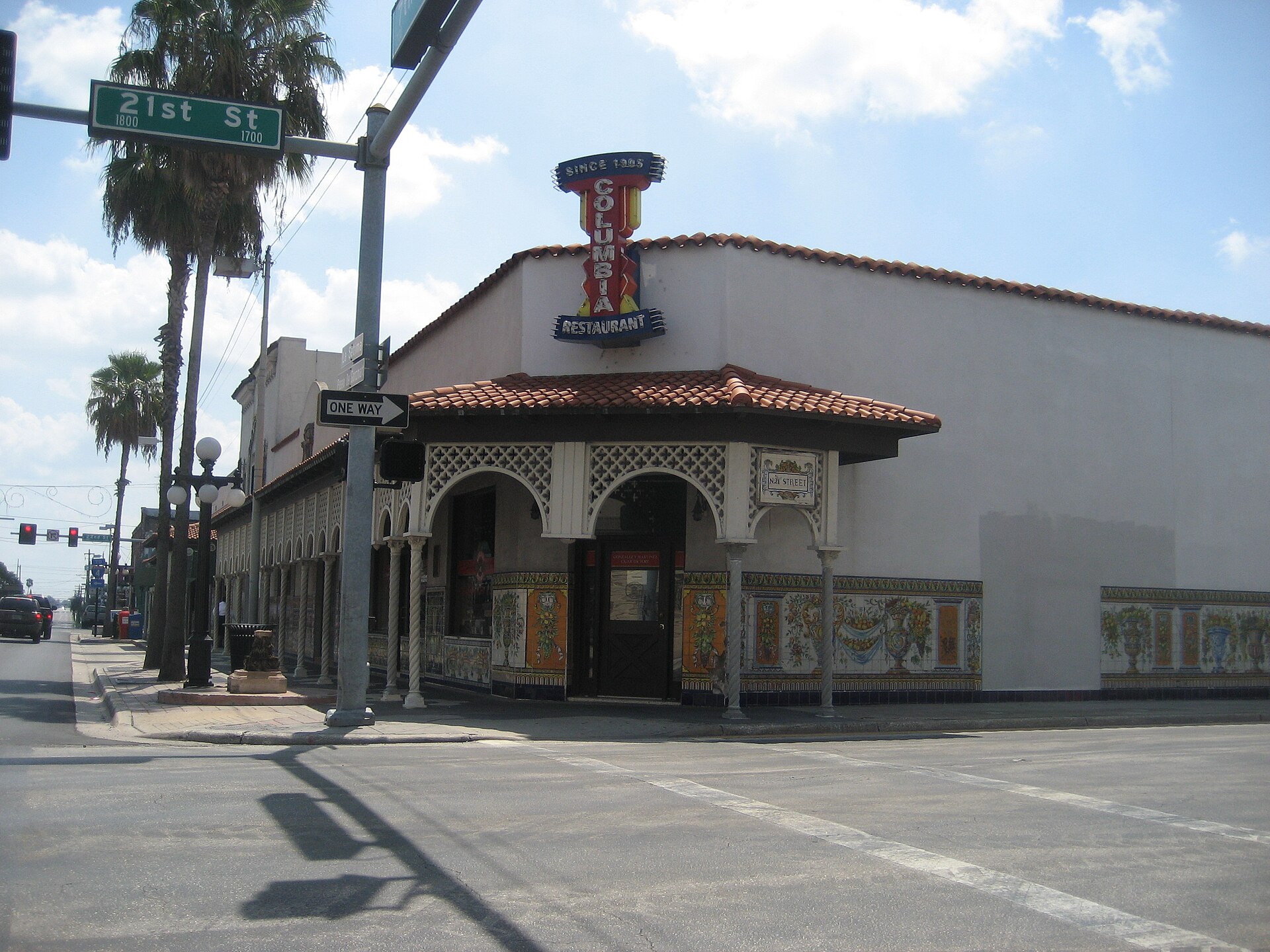 The tiled corner entrance of the Columbia Restaurant in Ybor City, with a vertical neon sign reading Columbia Restaurant Since 1905 and hand-painted Spanish tile panels