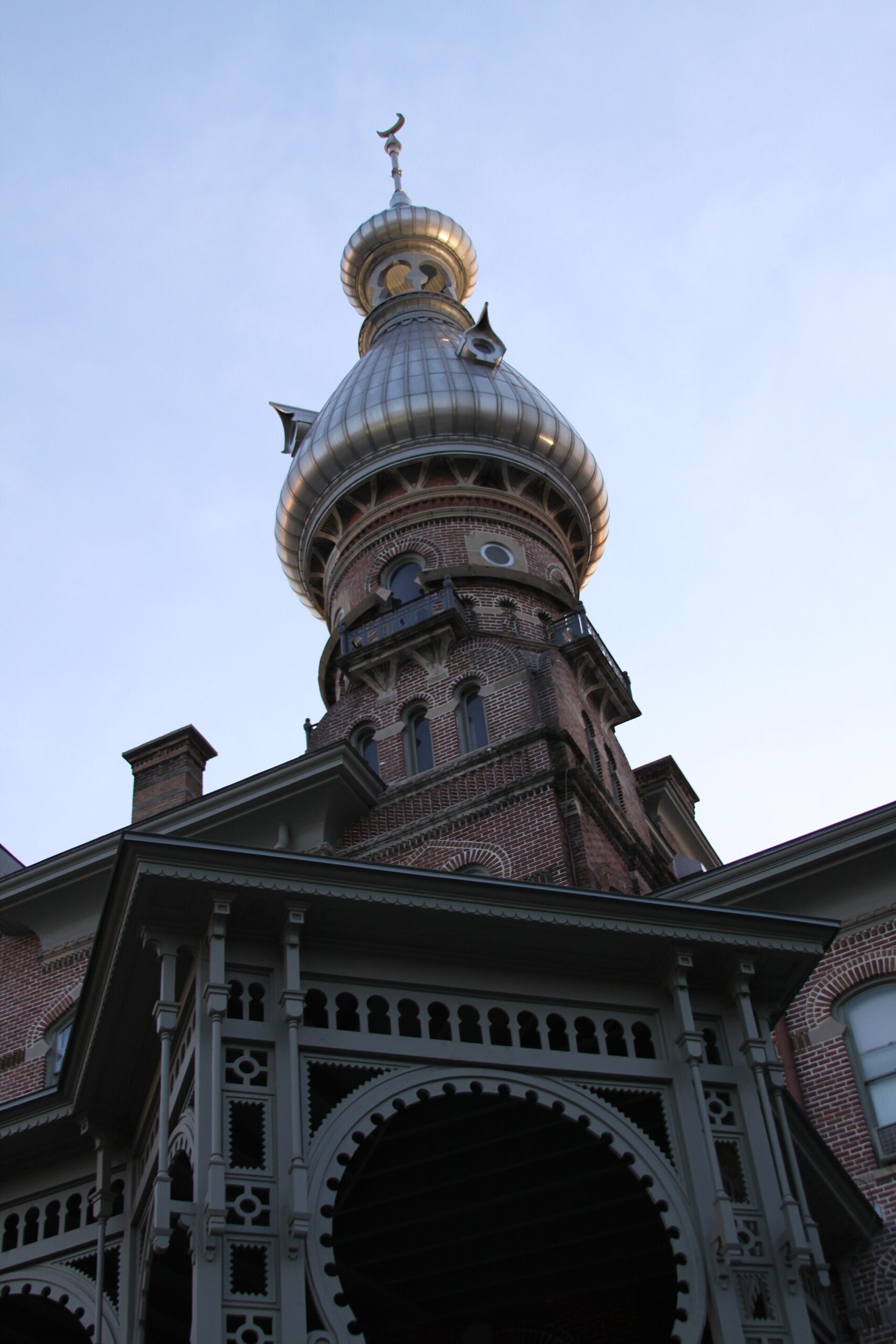 A silver onion-domed minaret with a crescent finial rising above the brick and ironwork of Plant Hall at the University of Tampa