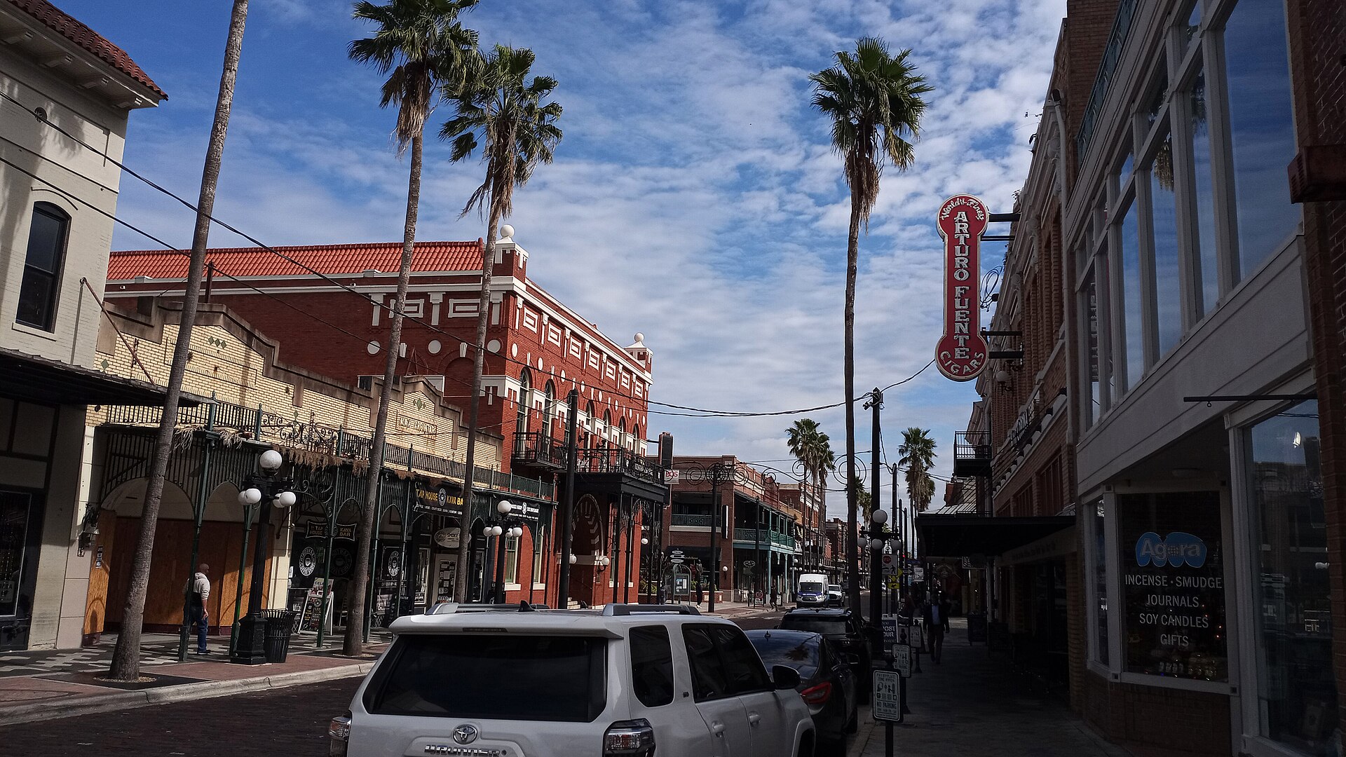 Seventh Avenue in Ybor City, with brick and stucco buildings, wrought-iron balconies, palm trees and a vertical Arturo Fuente Cigars sign above a shopfront