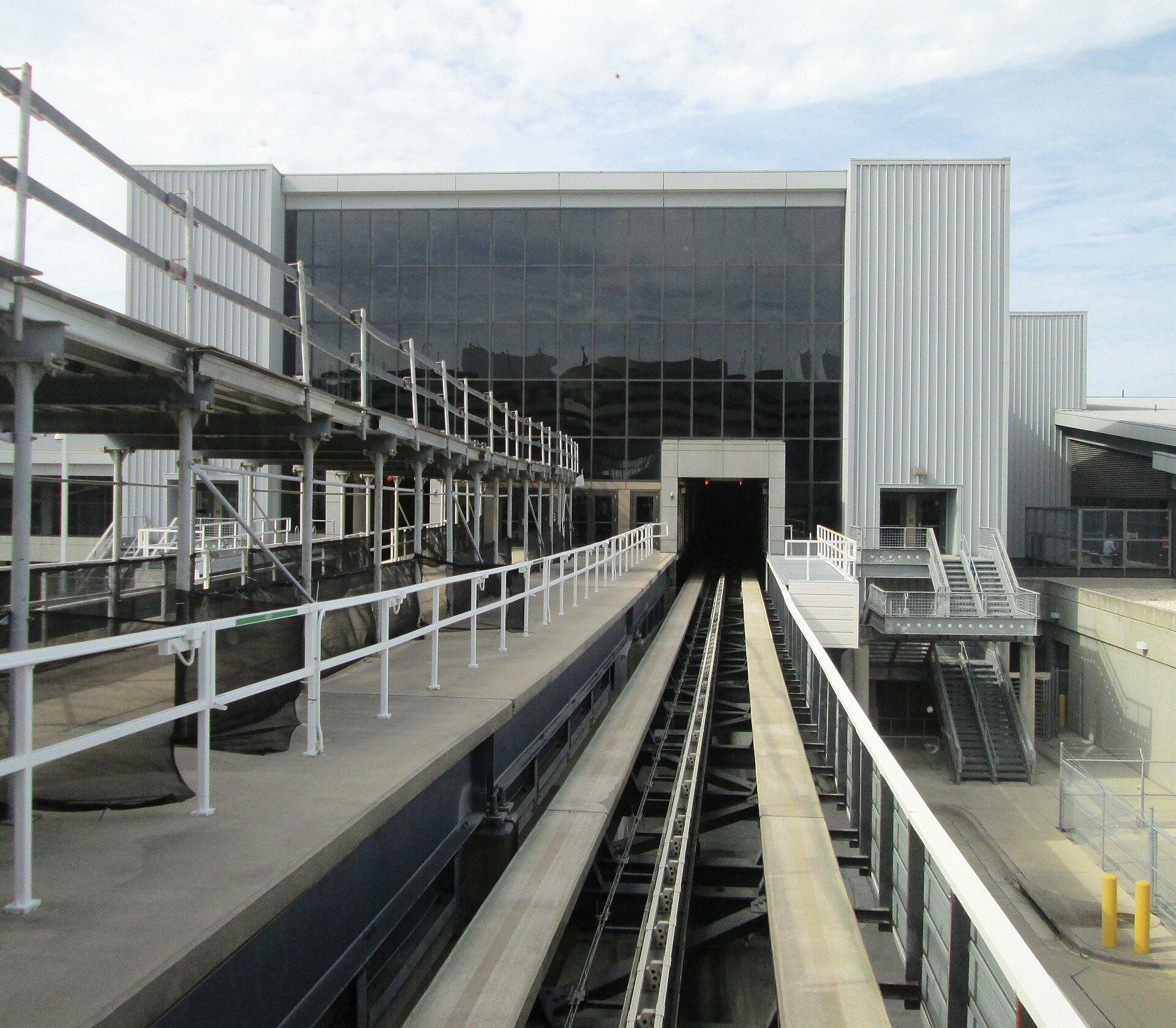An automated people mover guideway running toward a glass terminal building at Tampa International Airport