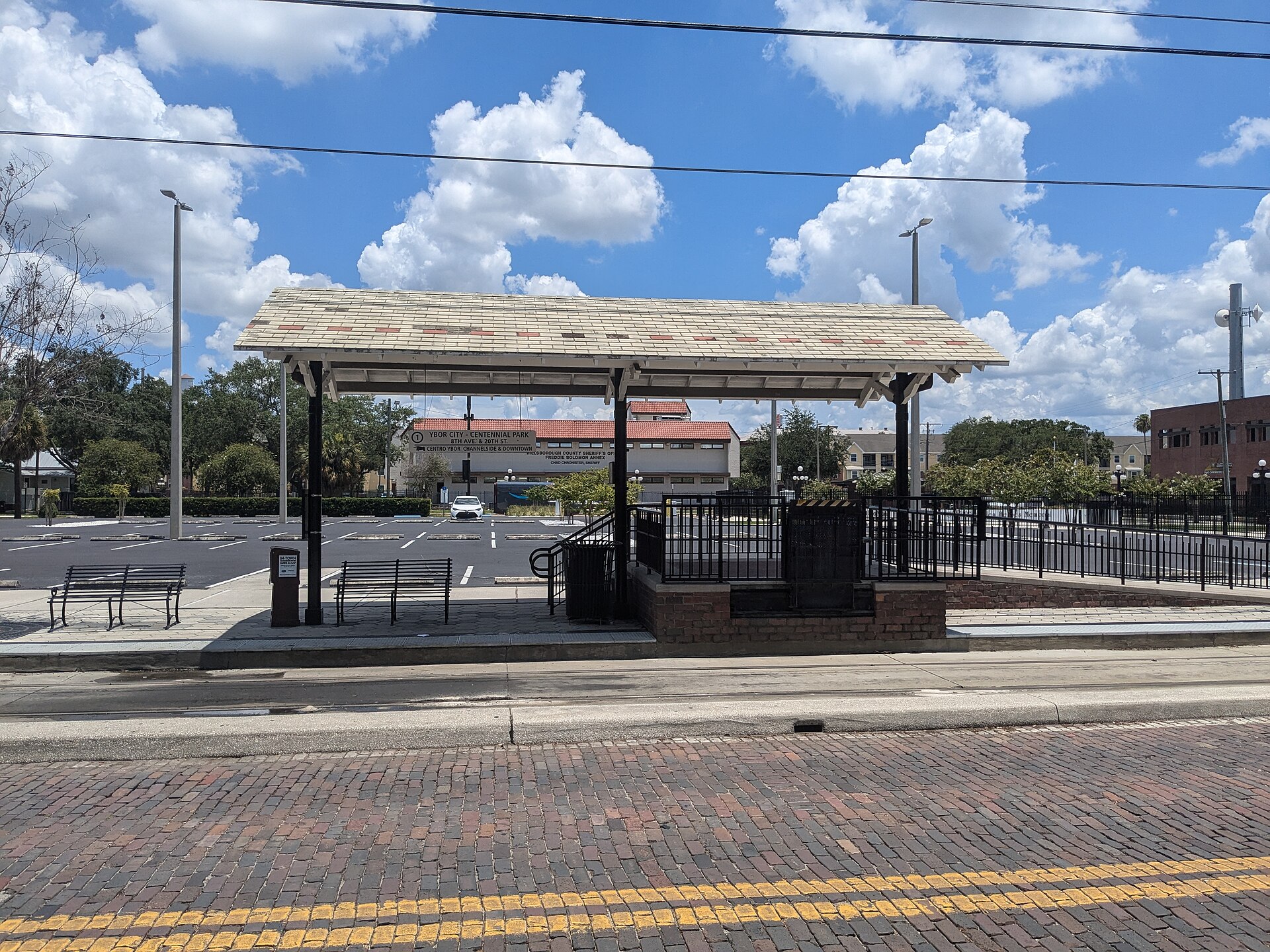 The covered Centennial Park streetcar station on 8th Avenue in Ybor City, with a brick street in the foreground and a sign naming the stop