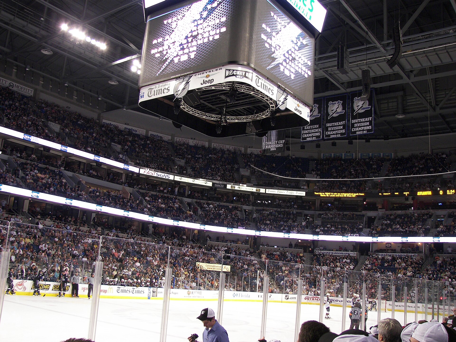 A Tampa Bay Lightning home game seen from rinkside seats, with the crowd filling the lower and upper bowls and championship banners hanging from the roof